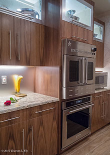 AFTER: Dual ovens integrated into cabinet work; illuminated glass front/metal frame cabinets above